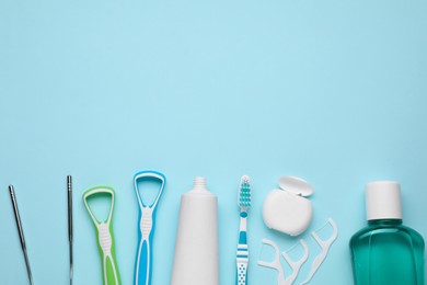 Photo of Tongue cleaners and other oral care products on light blue background, flat lay. Space for text