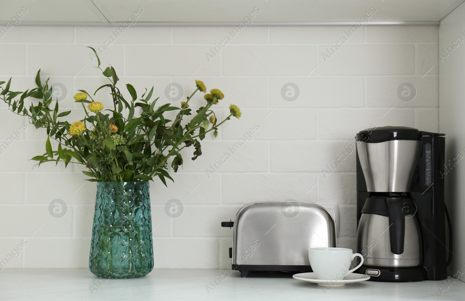 Photo of Modern toaster, coffeemaker and beautiful bouquet on countertop in kitchen