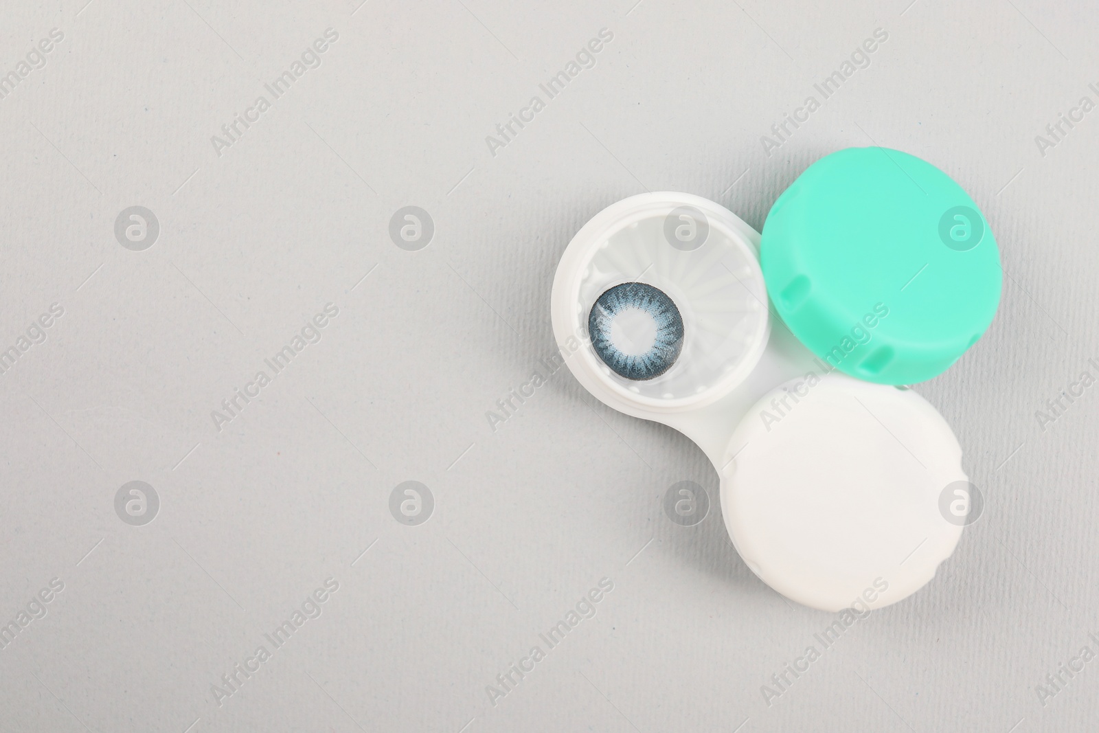 Photo of Case with blue contact lenses on light grey background, top view. Space for text