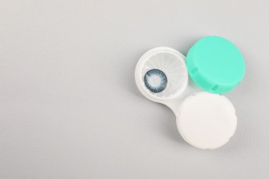 Photo of Case with blue contact lenses on light grey background, top view. Space for text