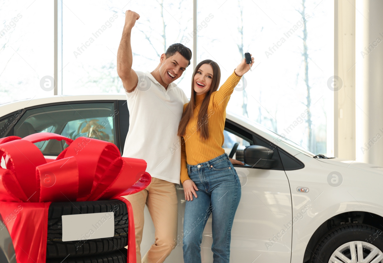 Photo of Happy couple with car key in modern auto dealership