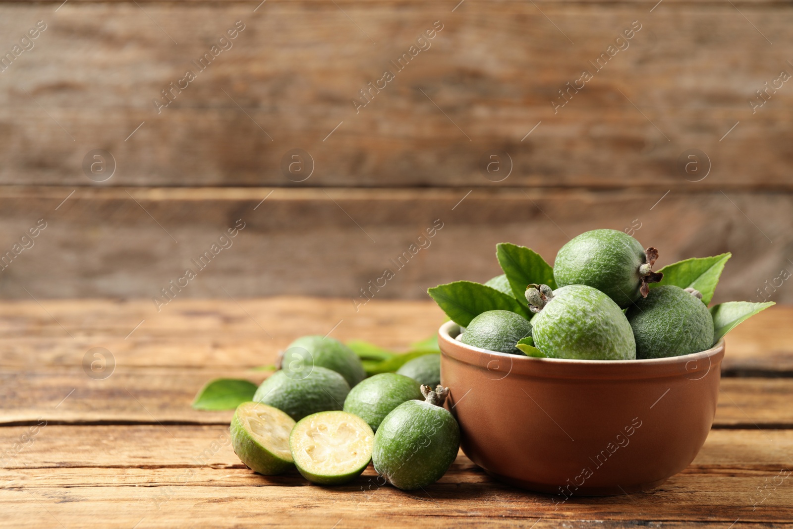 Photo of Fresh green feijoa fruits on wooden table, space for text