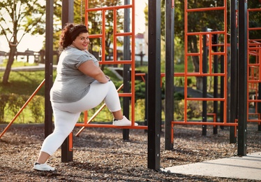 Beautiful overweight woman training on sports ground