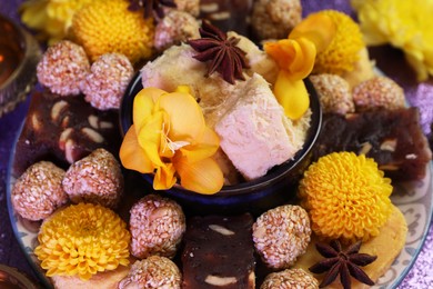 Photo of Diwali celebration. Tasty Indian sweets and flowers on table