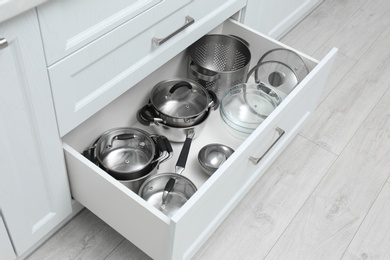 Photo of Open drawer with pots and pan indoors. Order in kitchen