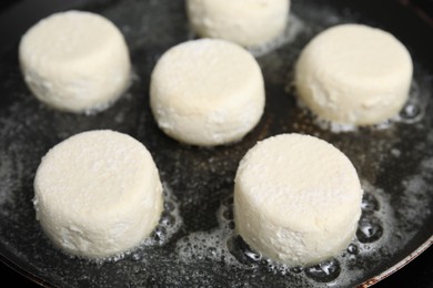 Uncooked cottage cheese pancakes in frying pan, closeup