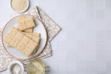 Photo of Delicious sweet kozinaki bars, honey and sesame seeds on white table, flat lay. Space for text