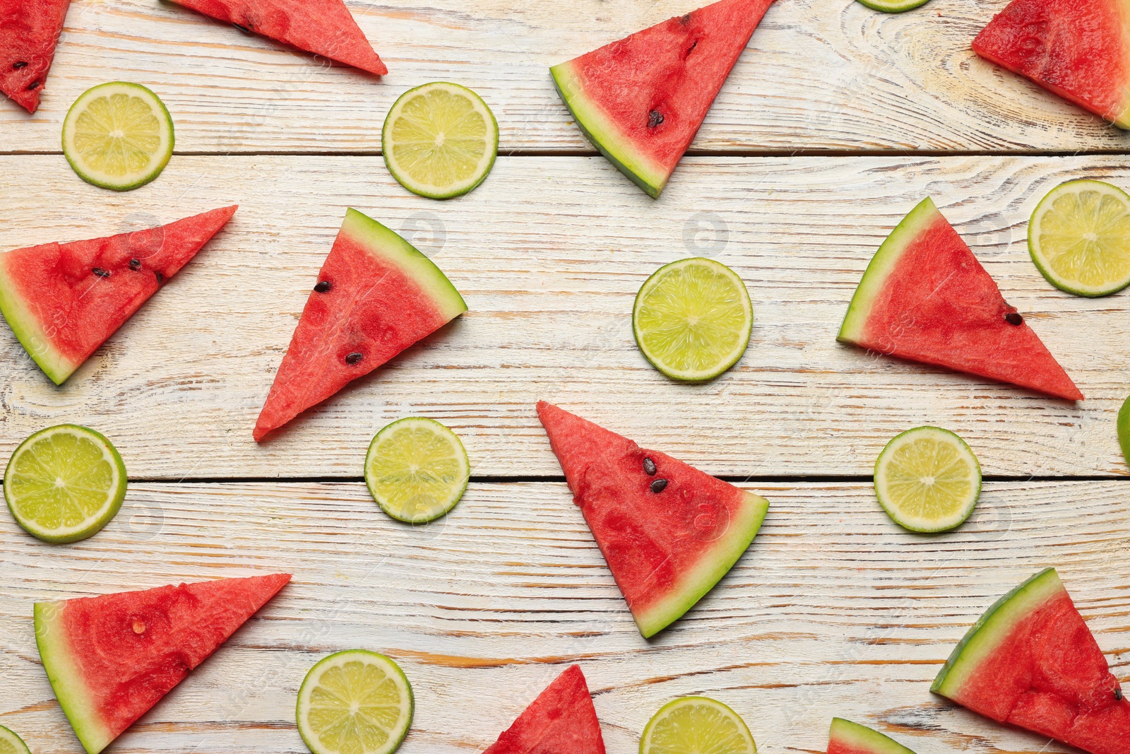Photo of Tasty sliced watermelon and limes on white wooden table, flat lay