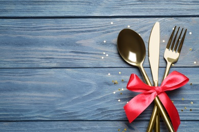 Cutlery set on blue wooden table, top view with space for text. Christmas celebration