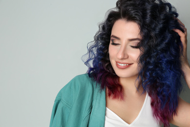 Photo of Young woman with bright dyed hair on light background