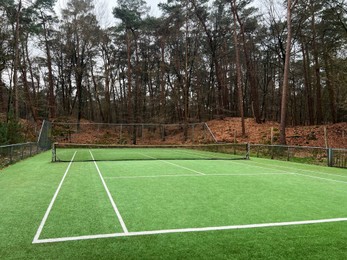 Photo of Tennis court with artificial grass and net outdoors