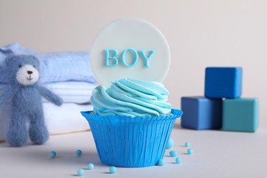Beautifully decorated baby shower cupcake for boy with cream and topper on light background