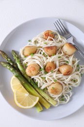 Delicious scallop pasta with asparagus, green onion and lemon served on white table, top view