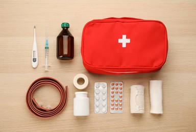 Photo of First aid kit on light wooden table, flat lay