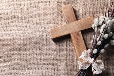 Cross and willow branches on beige cloth, flat lay. Space for text