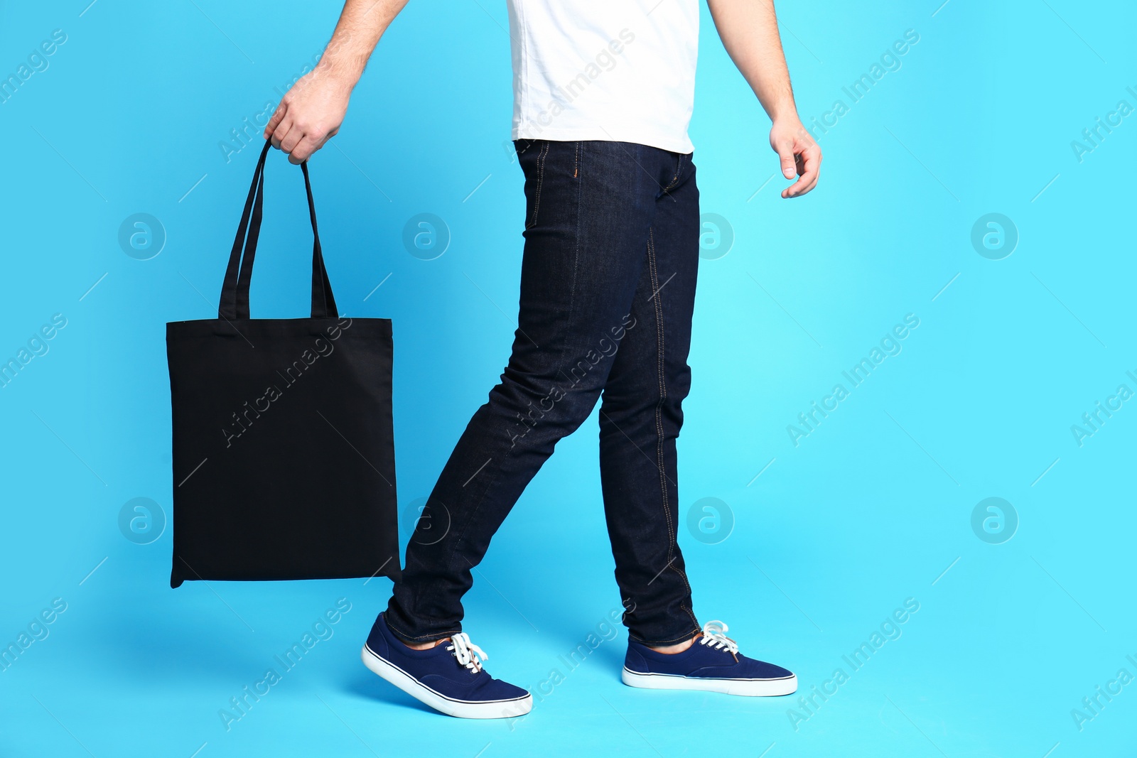 Photo of Young man with eco bag on blue background, closeup