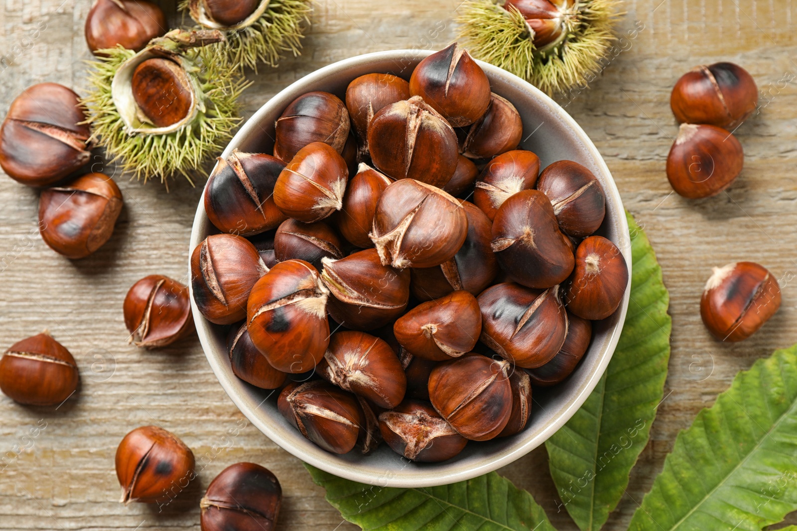 Photo of Delicious roasted edible chestnuts on wooden table, flat lay