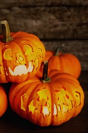 Image of Spooky jack o`lanterns on wooden table, closeup. Halloween decor
