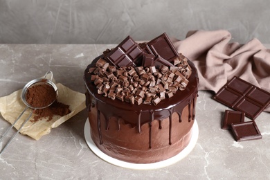 Photo of Freshly made delicious chocolate cake on marble table against grey background