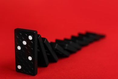 Black domino tiles falling on red background. Space for text