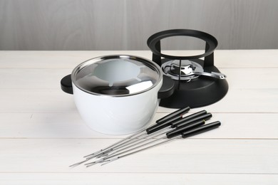 Fondue set on white wooden table. Kitchen equipment