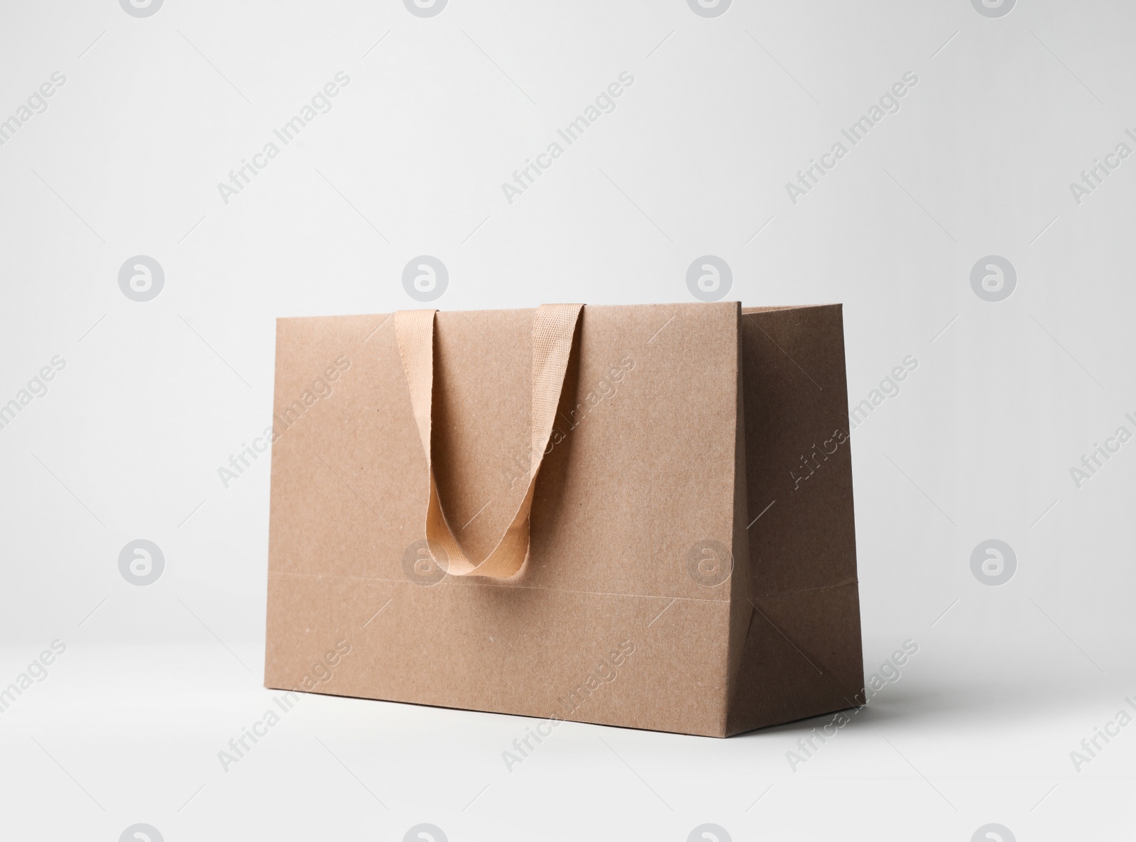 Photo of Paper shopping bag with comfortable handles on white background. Mockup for design