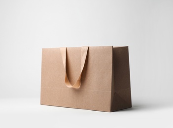 Photo of Paper shopping bag with comfortable handles on white background. Mockup for design