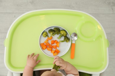 Photo of Cute little baby eating healthy food, top view