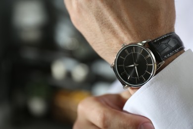 Photo of Man with luxury wrist watch on blurred background, closeup. Space for text