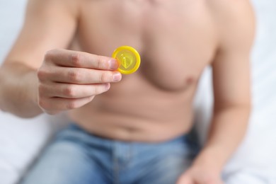 Photo of Closeup view of man showing condom on white background
