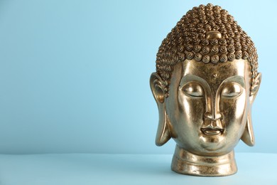 Photo of Beautiful golden Buddha sculpture on light blue background. Space for text