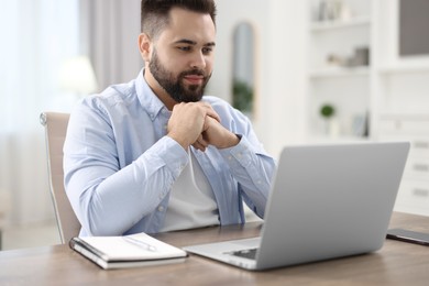 Young man watching webinar at table in room