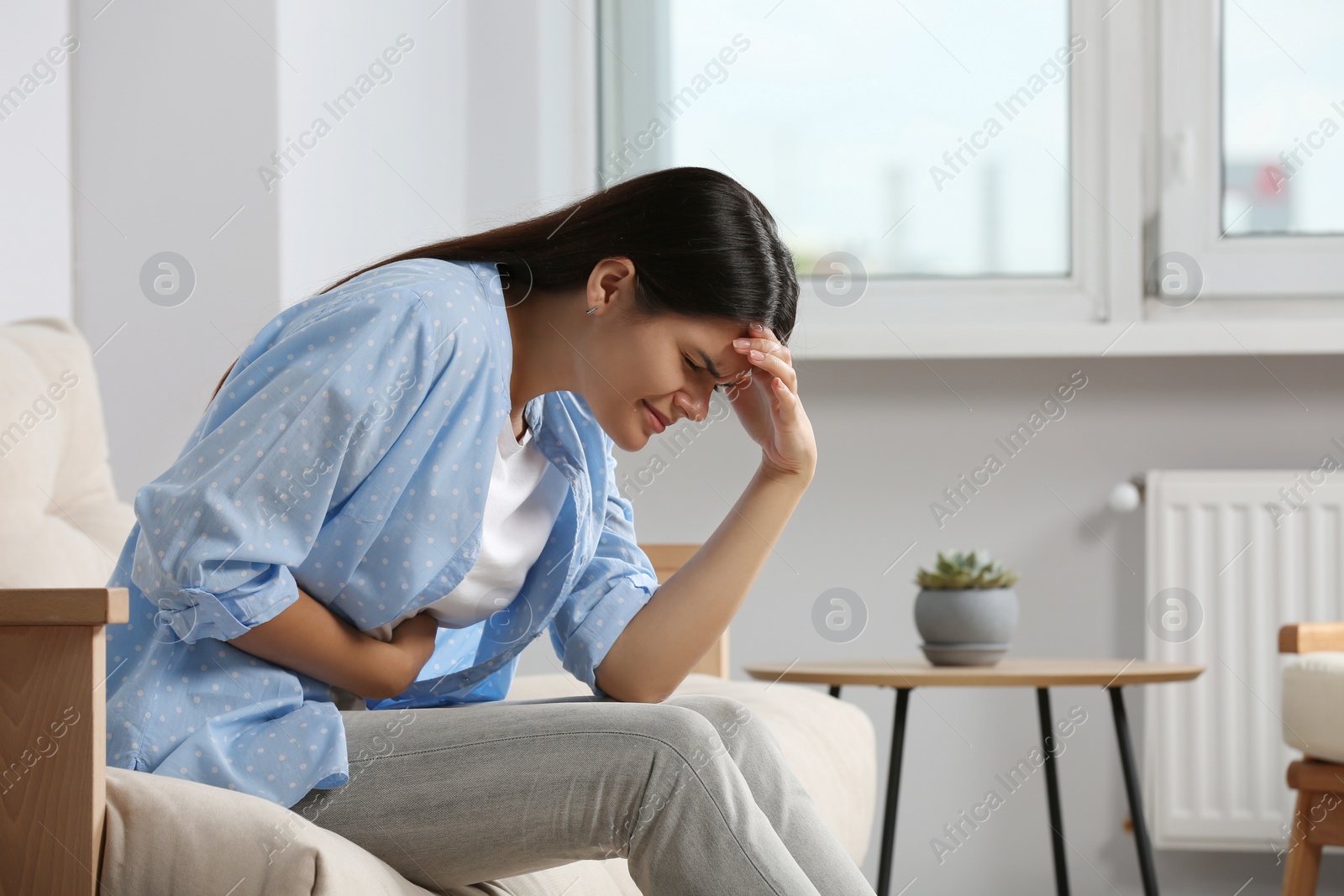 Photo of Young woman suffering from menstrual pain at home