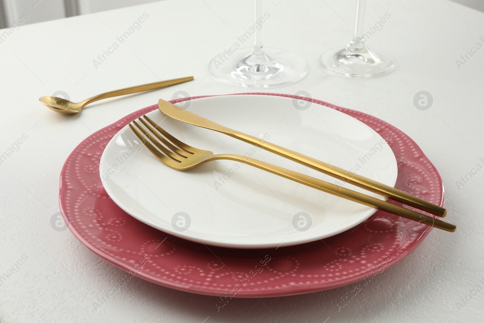 Photo of Stylish setting with cutlery and plates on white textured table