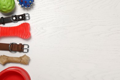 Photo of Flat lay composition with dog collars and toys on white wooden table. Space for text
