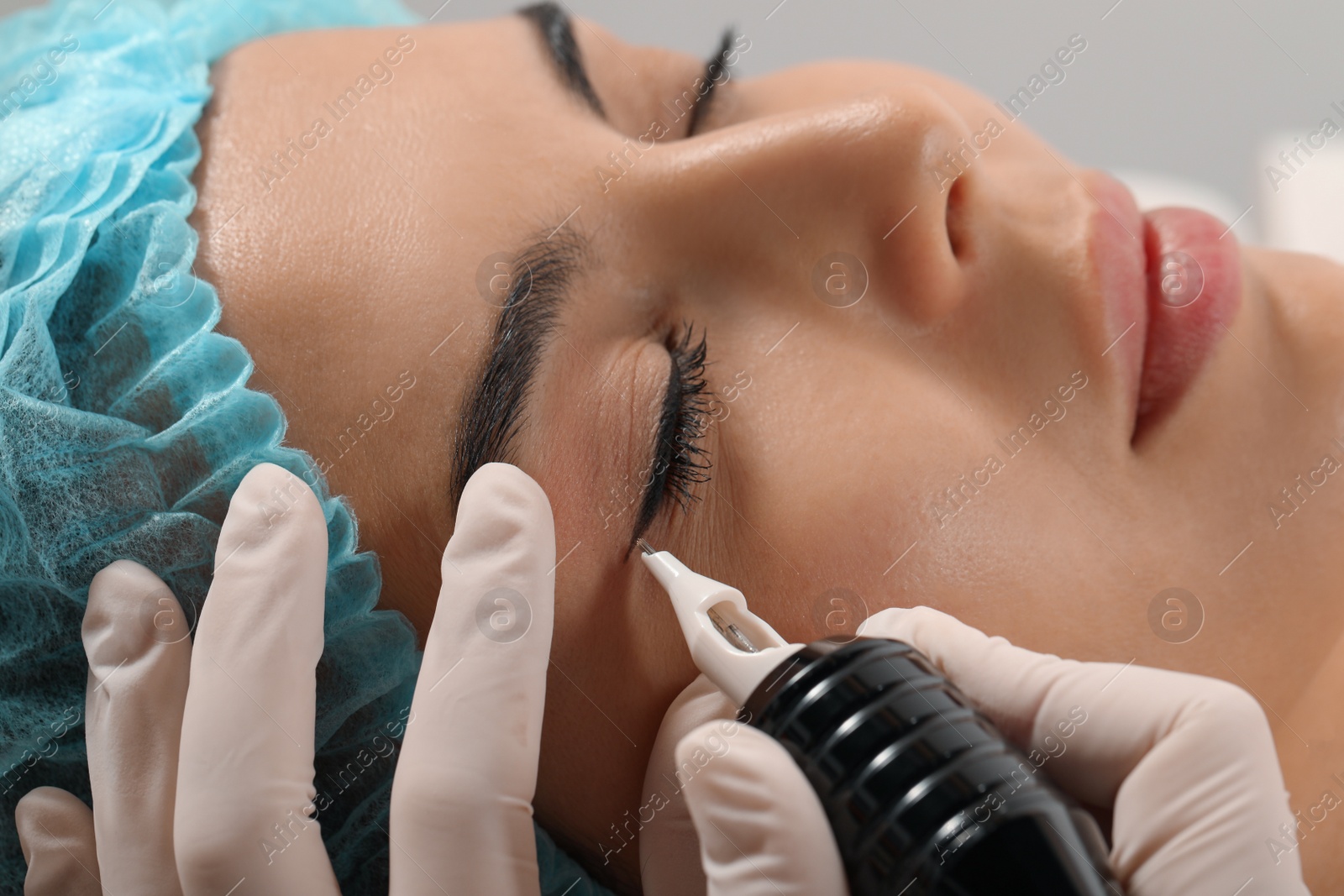 Photo of Young woman undergoing procedure of permanent eyeliner makeup, closeup