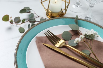 Photo of Stylish table setting with cutlery, flower and eucalyptus leaves, closeup