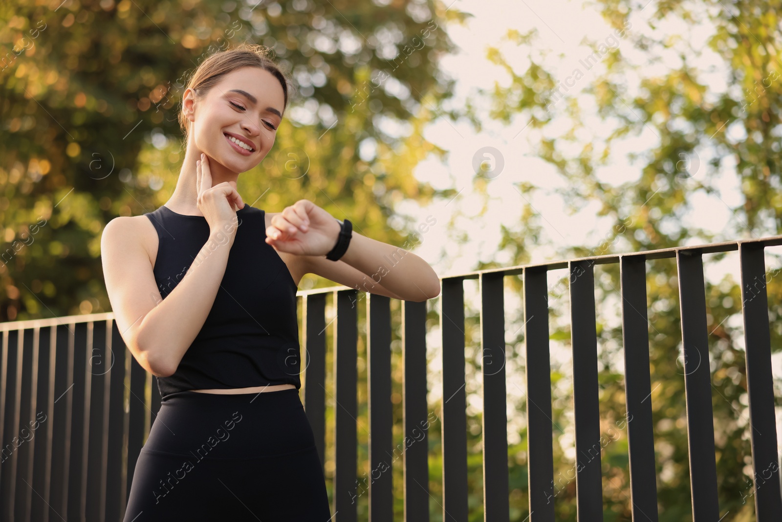 Photo of Attractive happy woman checking pulse after training in park. Space for text