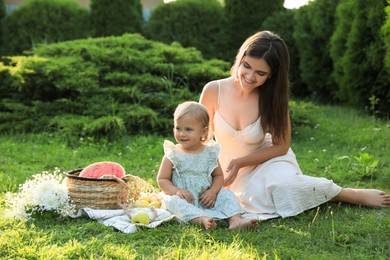 Photo of Mother with her baby daughter having picnic in garden on sunny day