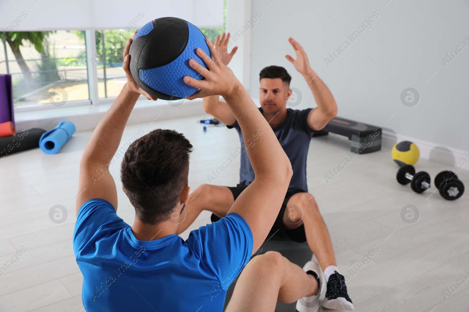 Photo of Muscular men exercising with medicine ball in modern gym