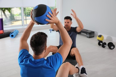 Muscular men exercising with medicine ball in modern gym