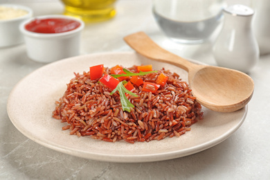 Photo of Tasty brown rice with pepper and arugula on light grey marble table