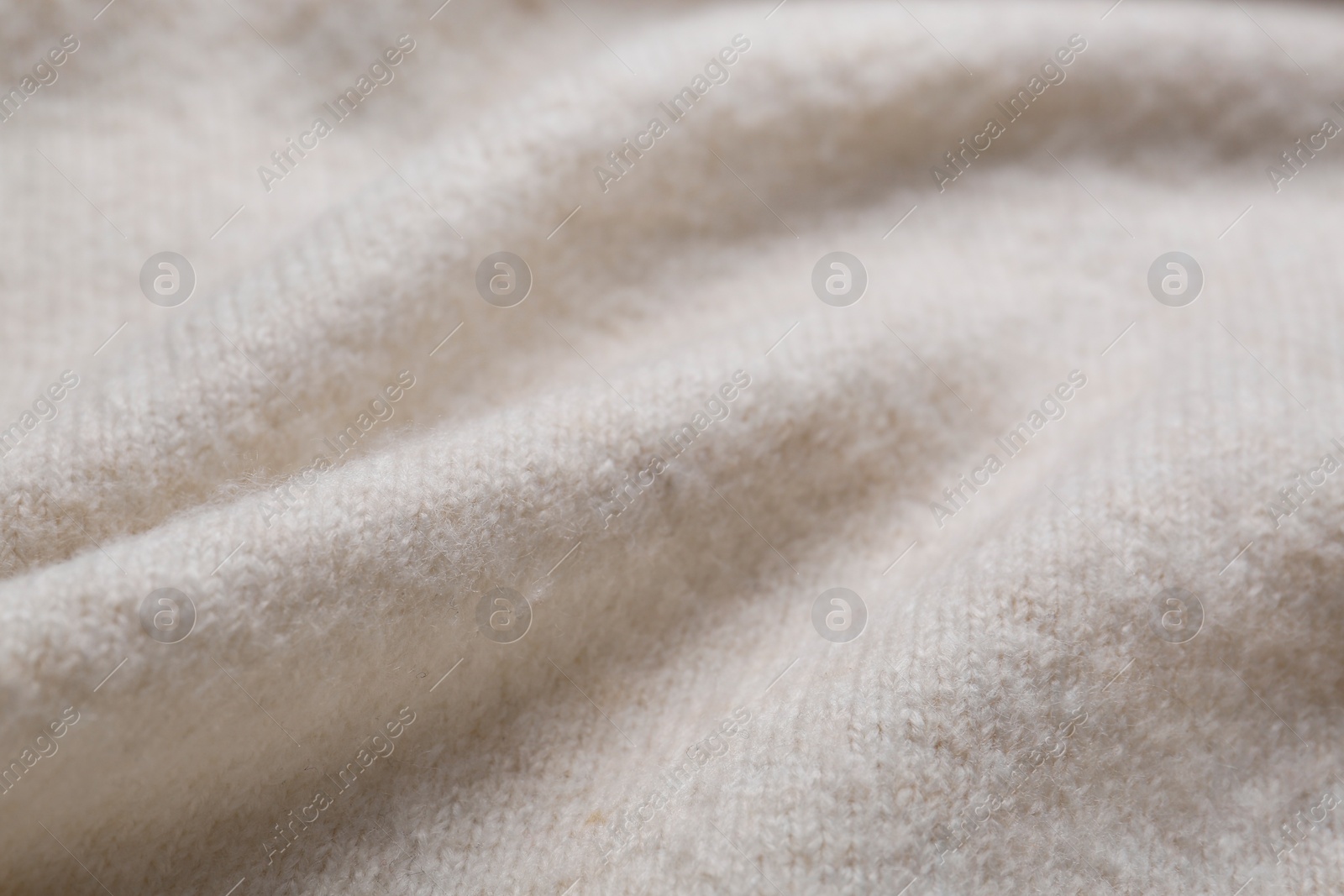 Photo of Soft beige knitted fabric as background, closeup