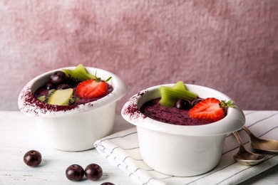 Photo of Bowls with tasty acai smoothie on light table