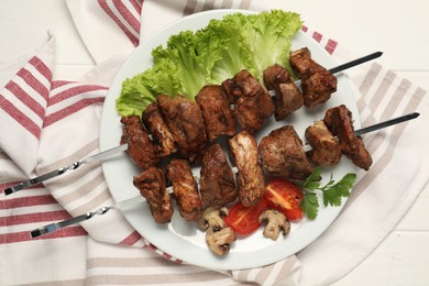 Photo of Delicious shish kebabs with vegetables on white wooden table, flat lay