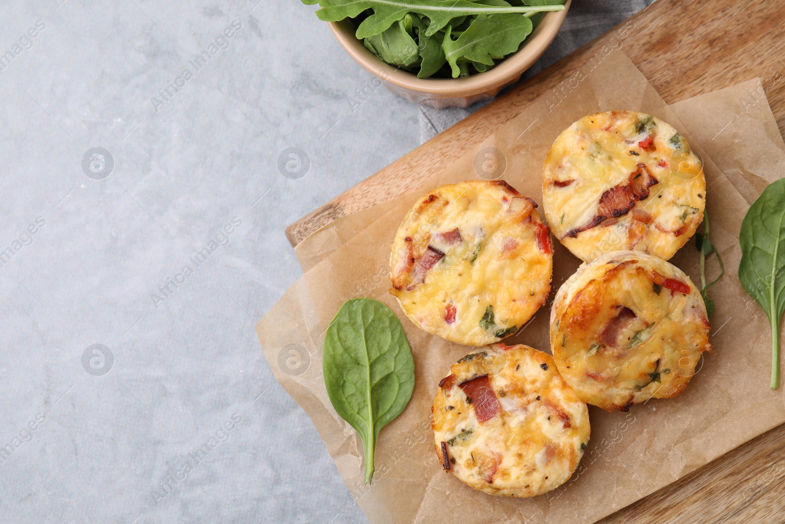 Photo of Delicious egg muffins with cheese and bacon on grey table, flat lay. Space for text