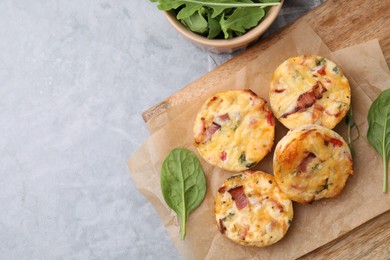 Photo of Delicious egg muffins with cheese and bacon on grey table, flat lay. Space for text