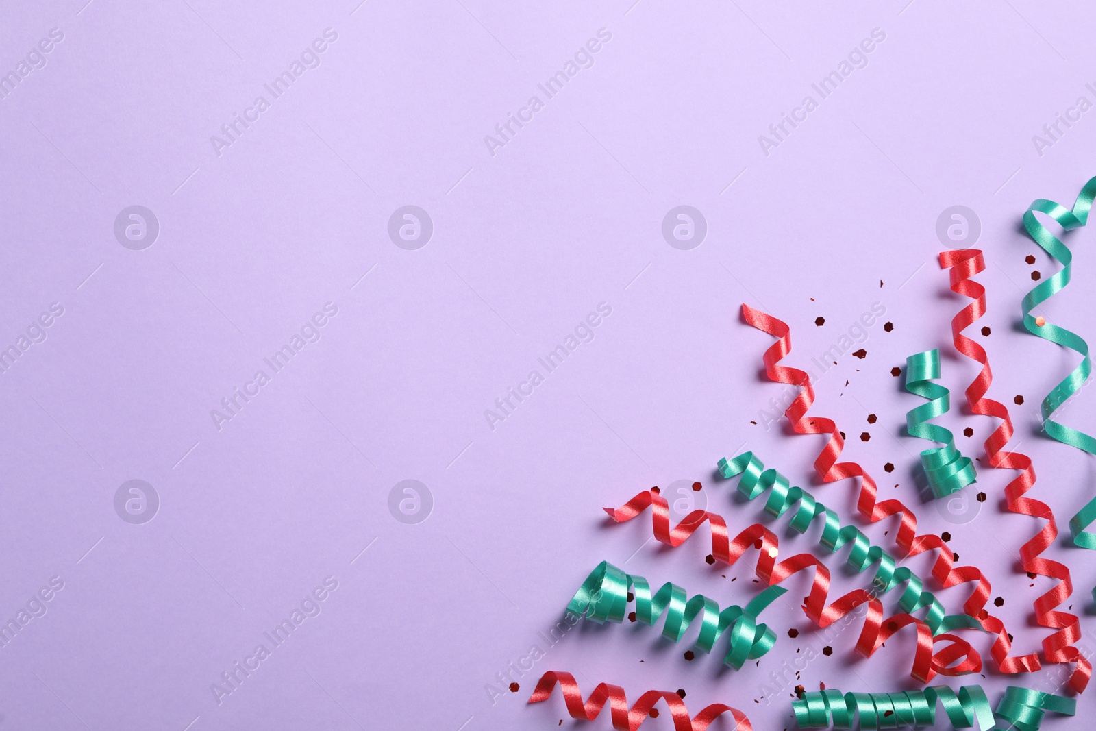 Photo of Colorful serpentine streamers and confetti on light background, flat lay. Space for text