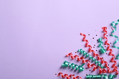 Photo of Colorful serpentine streamers and confetti on light background, flat lay. Space for text