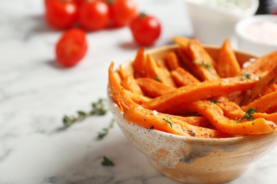 Bowl with sweet potato fries on table, space for text